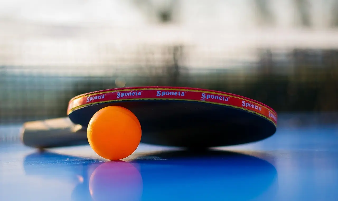 Bordtennisbat og orange bold på et bord